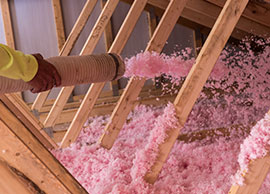 Installer blowing fiberglass insulation into attic