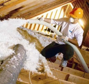 Installer blowing fiberglass insulation into attic